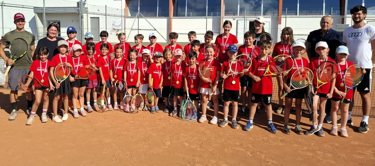 Tennis-Nachwuchs mit Medaillen und Schlägern auf Sandplatz