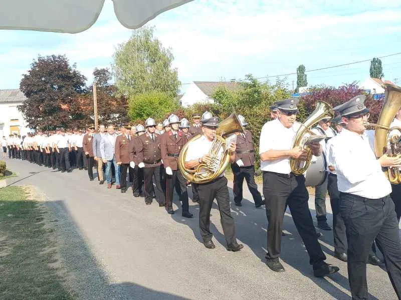 Feuerwehrkapelle marschiert in Uniform mit Instrumenten durch eine Ortschaft