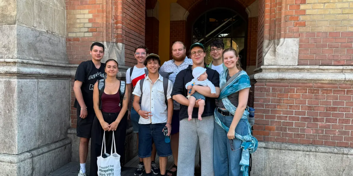 Gruppe junger Leute mit Baby vor Ziegelsteingebäude in Wien