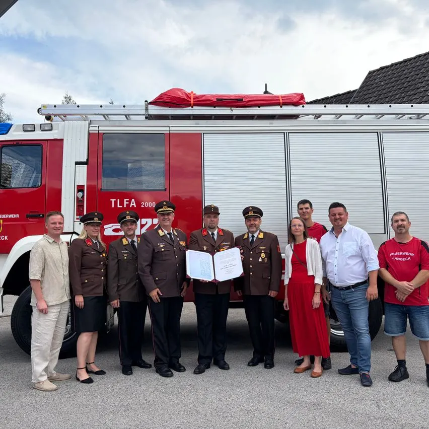 Feuerwehrleute in Uniformen vor einem TLFA 2000 in Langegg bei Schärding mit Dokumenten