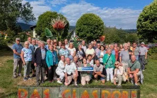 Gruppe von Senioren vor dem Schild "Das Glasdorf" in Neugablonz, Deutschland