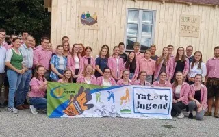 Jugendliche und Betreuer der "Tatort Jugend" in Trachten vor Holzhütte in Österreich.