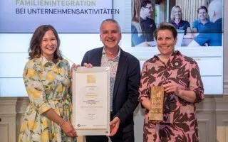 Familienintegration: Zwei Frauen und ein Mann mit Urkunde und Holzpreis in Wien