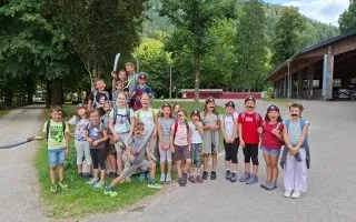 Kinder mit Schnurrbärten und Spielzeugschwertern vor einem Gebäude in einem Wald