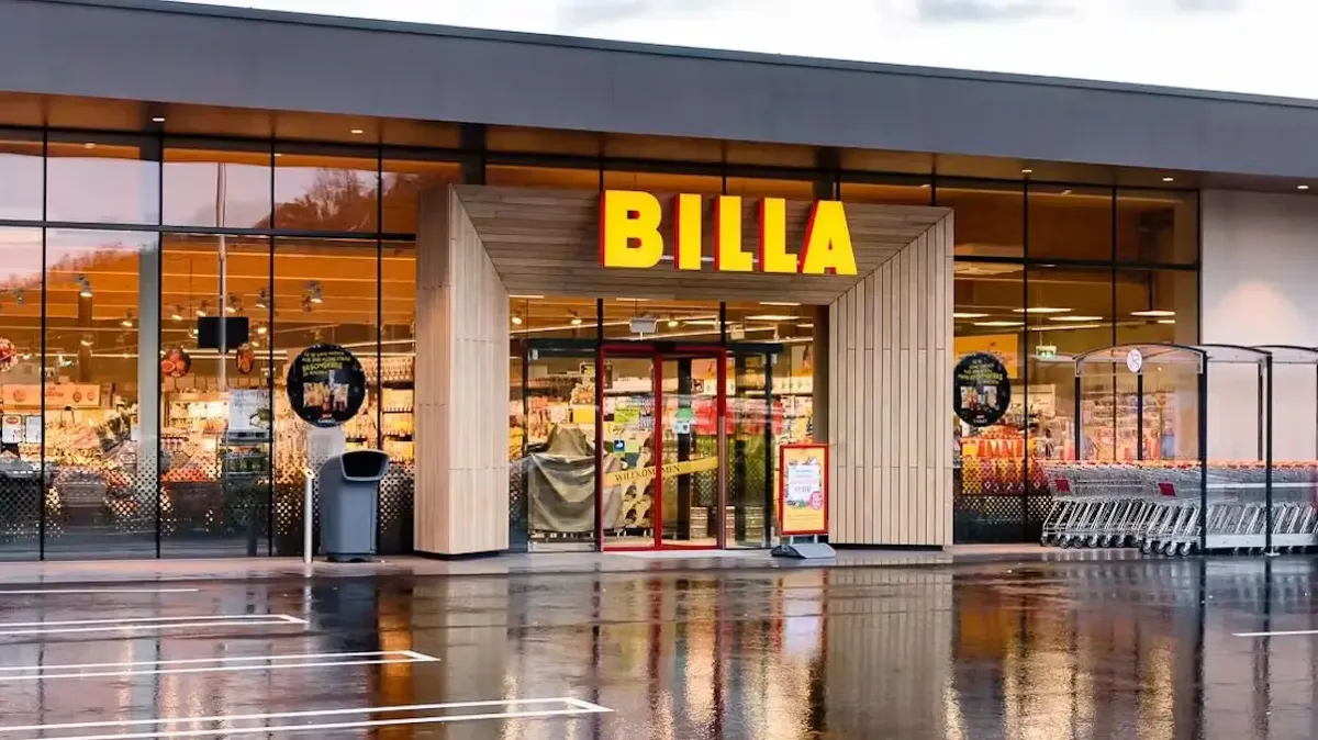 Billa-Supermarkt in Österreich mit Einkaufswägen und nassem Parkplatz