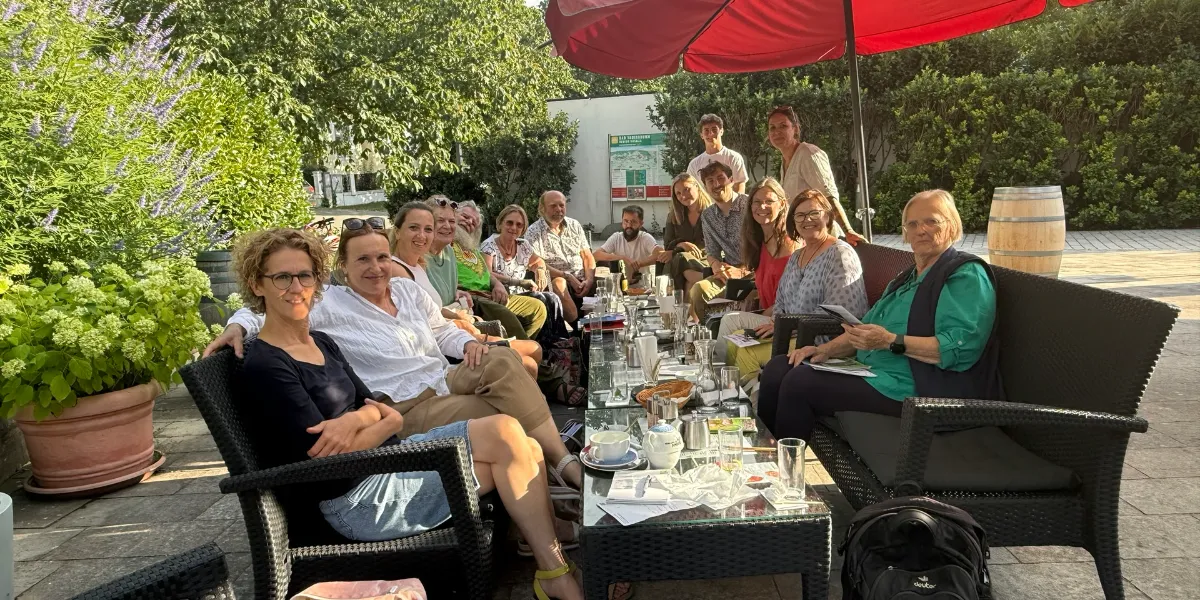 Gruppe von Menschen sitzt im Freien an einem Tisch mit Getränken und Snacks.