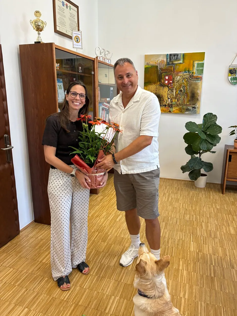 Frau mit Blumenstrauß und Mann in Büro in Österreich.