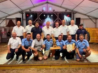 Feuerwehrleute mit Pokal und Urkunde in Österreich bei einem Fest im Zelt
