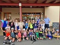 Kindergruppe mit Betreuern vor einem Gebäude in Österreich, einige winken.