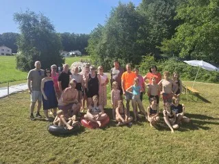 Gruppe von Menschen im Sommer in einem Park in Österreich mit Bäumen und Sonnenschirm.