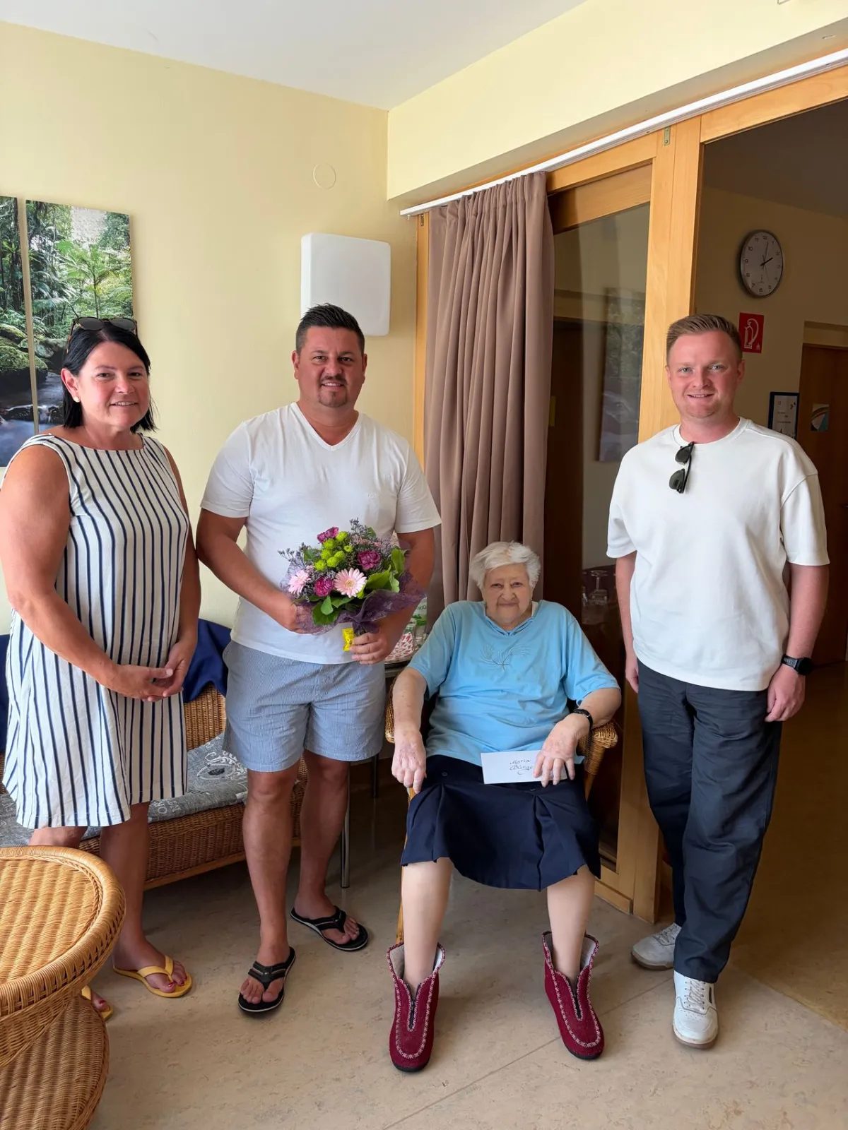 Frau mit Blumenstrauß und Familie in einem Raum