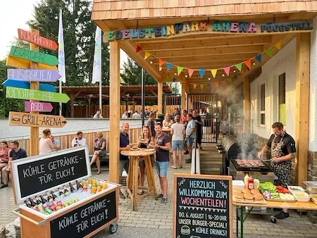 Grill-Arena Püggstall mit Gästen, cooler Getränkekiste und Schildern zu Kontinenten