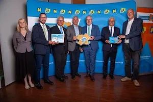 Gruppe mit Funktionären und Auszeichnungen vor blauem Banner mit "NÖ" und "Niederösterreich" Schriftzug