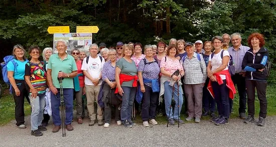 Wandergruppe steht vor Wegweisern in der Natur