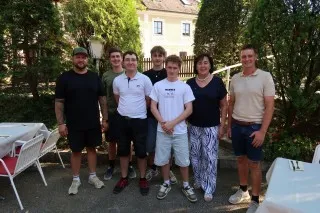 Gruppe von jungen Männern und zwei Frauen posiert auf einer Terrasse in Österreich.