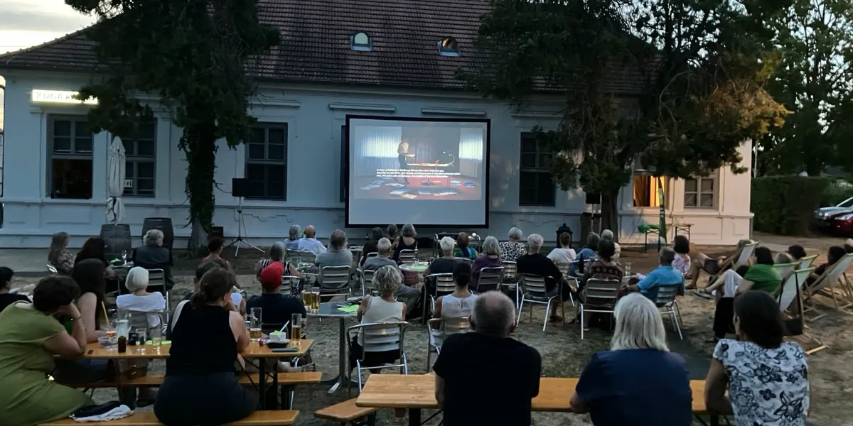 Open-Air-Kino in Wien: Publikum schaut Filmvorführung im Freien vor einem Gebäude