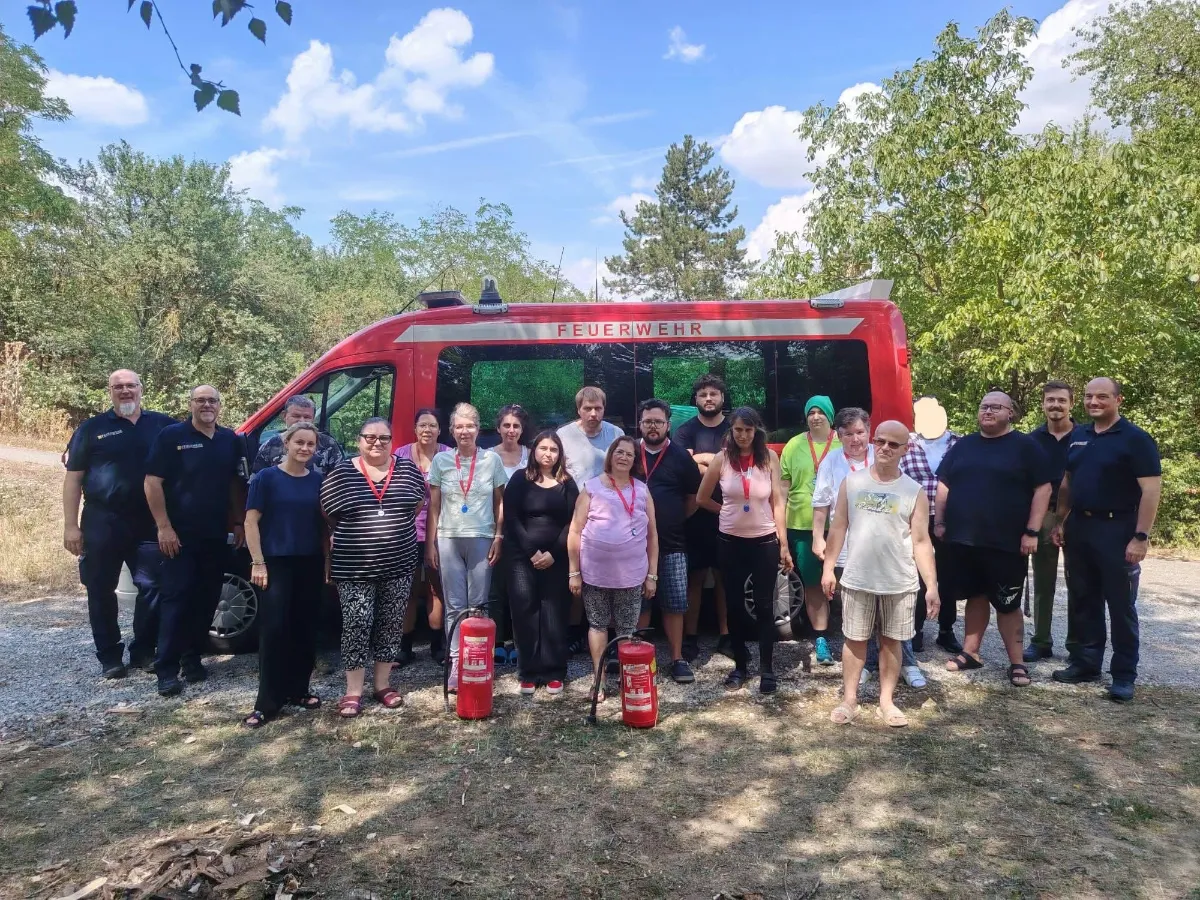 Feuerwehr-Team mit Einsatzfahrzeug und zwei Feuerlöschern vor Bäumen