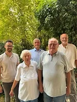 Fünf Personen stehen vor Bäumen, darunter ein älteres Ehepaar und drei Männer.