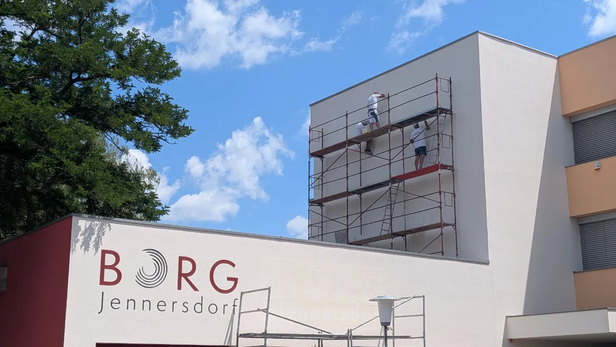 Handwerker renovieren BORG Jennersdorf mit Gerüst vor sonnigem Himmel