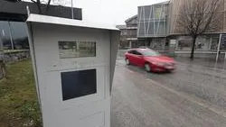 Blitzer an einer Straße in Österreich mit vorbeifahrendem roten Auto.
