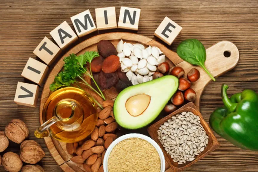 Vitamin E-reiche Lebensmittel wie Nüsse, Samen, Avocado und Öl auf Holzuntergrund