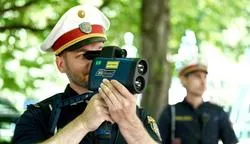 Polizist misst Geschwindigkeit mit Radarmessgerät in Wien, ein Kollege im Hintergrund.