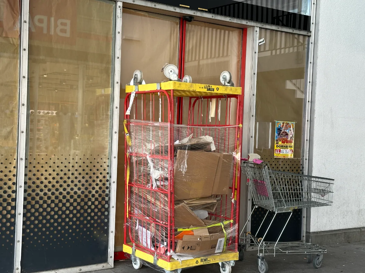 Verpackter Einkaufswagen mit Kartons und einem weiteren Einkaufswagen vor einer Tür in Dornbirn