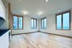 Leeres Wohnzimmer mit Parkettboden und großen Fenstern in Wien