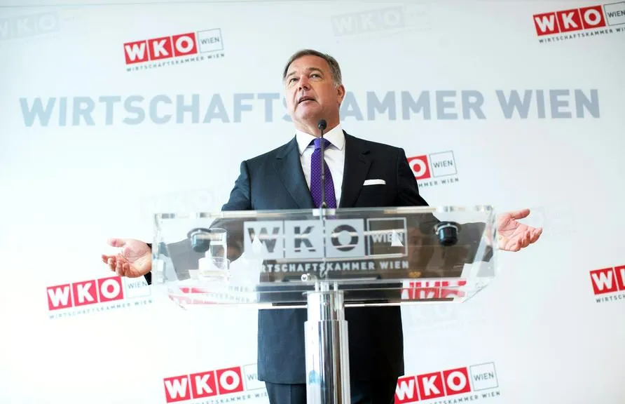 Wirtschaftskammer Wien Präsident mit erhobenen Armen hinter einem transparenten Rednerpult