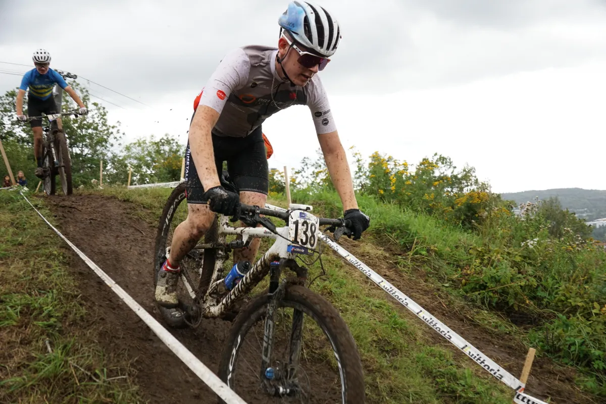 Mountainbiker mit Startnummer 138 fährt auf schlammiger Strecke bergab.