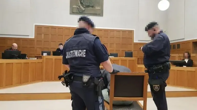 Justizwachebeamte führen eine Person in einem Gerichtssaal in Österreich ab.