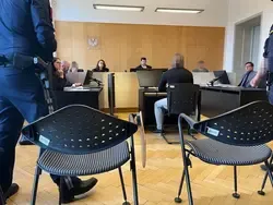 Gerichtssaal in Wien: Angeklagter sitzt vor Richtertribunal, Polizisten im Vordergrund.