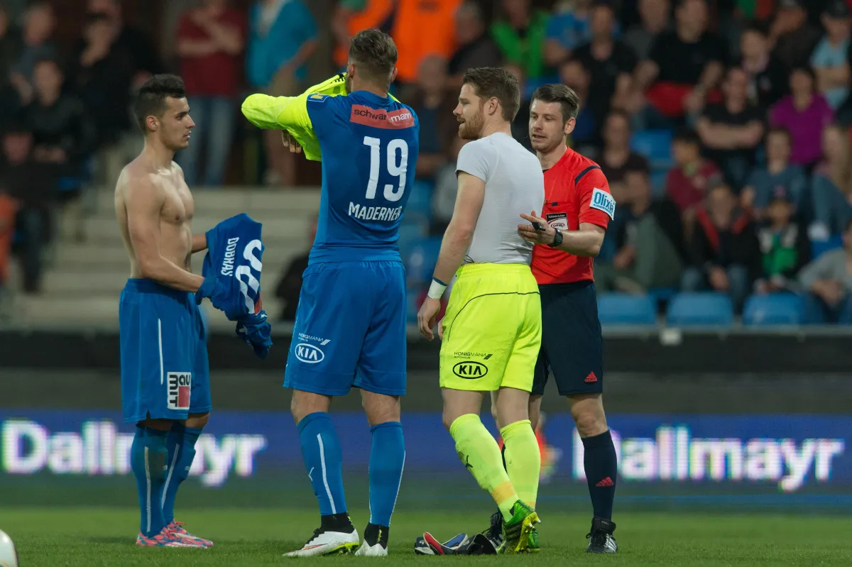 Fußballer Madener mit Trikot, Schiedsrichter und Spieler auf einem Rasen in Österreich
