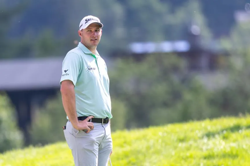 Golfer Justin Thomas mit weißer Kappe und hellgrünem Poloshirt auf einem Golfplatz