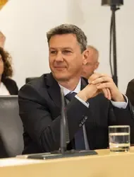 Gerhard Karner, Finanzminister, sitzt bei einer Veranstaltung in einem dunklen Anzug mit Krawatte.