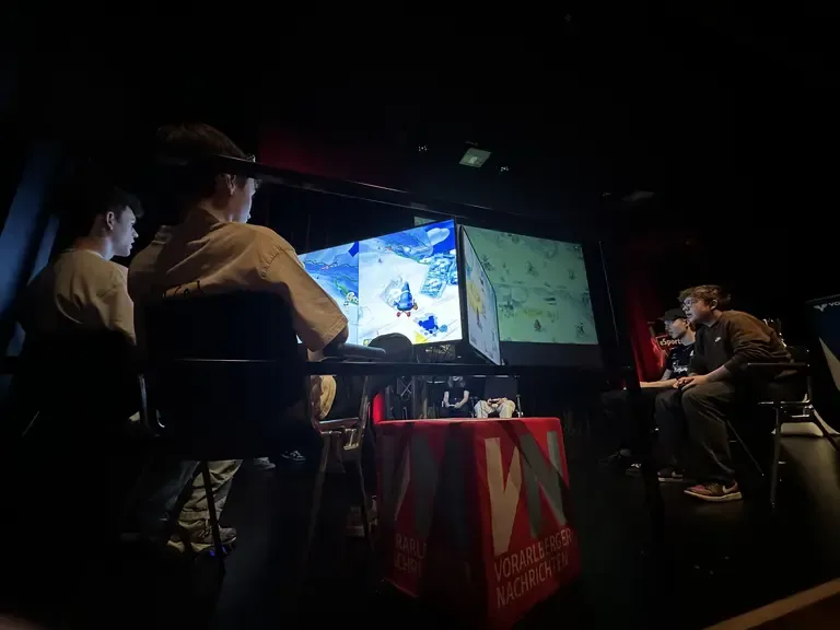 E-Sport-Turnier in Vorarlberg: Junge Männer spielen vor großen Bildschirmen.
