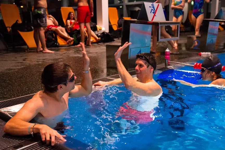 Schwimmer geben sich im Schwimmbecken in Wien Händchen, andere Personen ruhen sich aus
