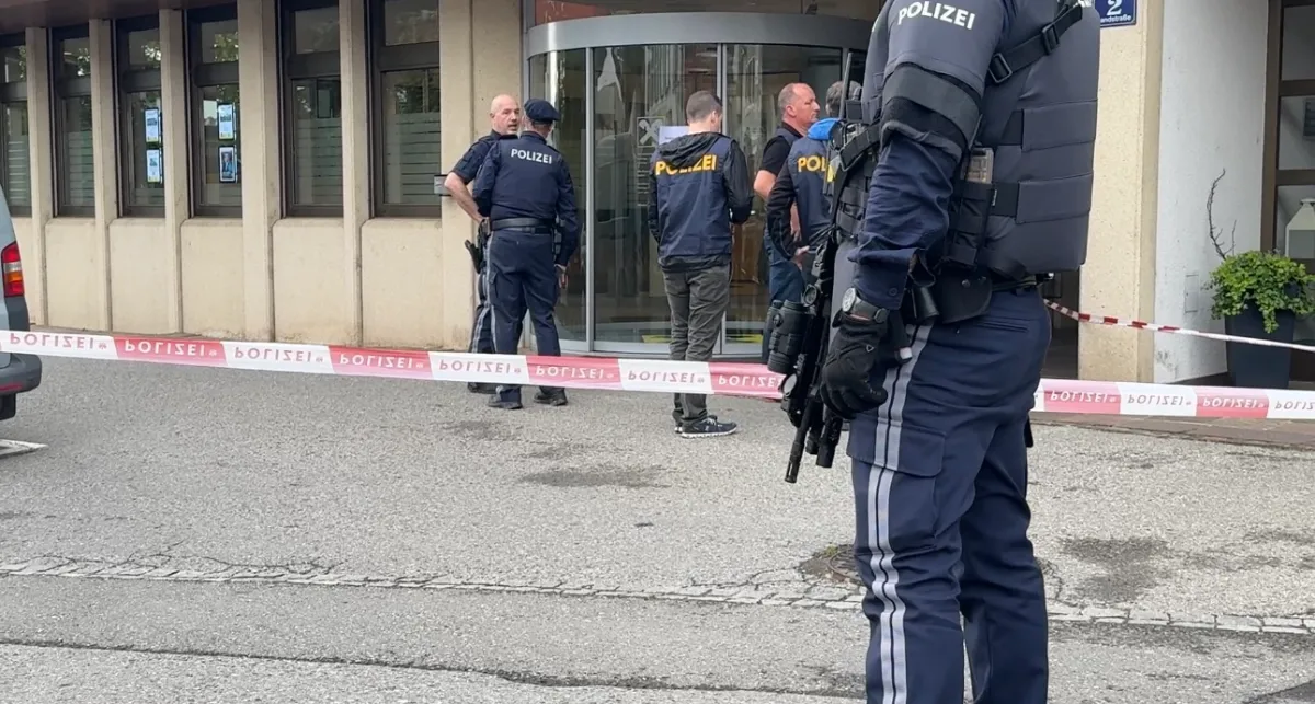 Polizeiabsperrung vor einem Gebäude mit mehreren Beamten in Uniform und Schutzausrüstung.