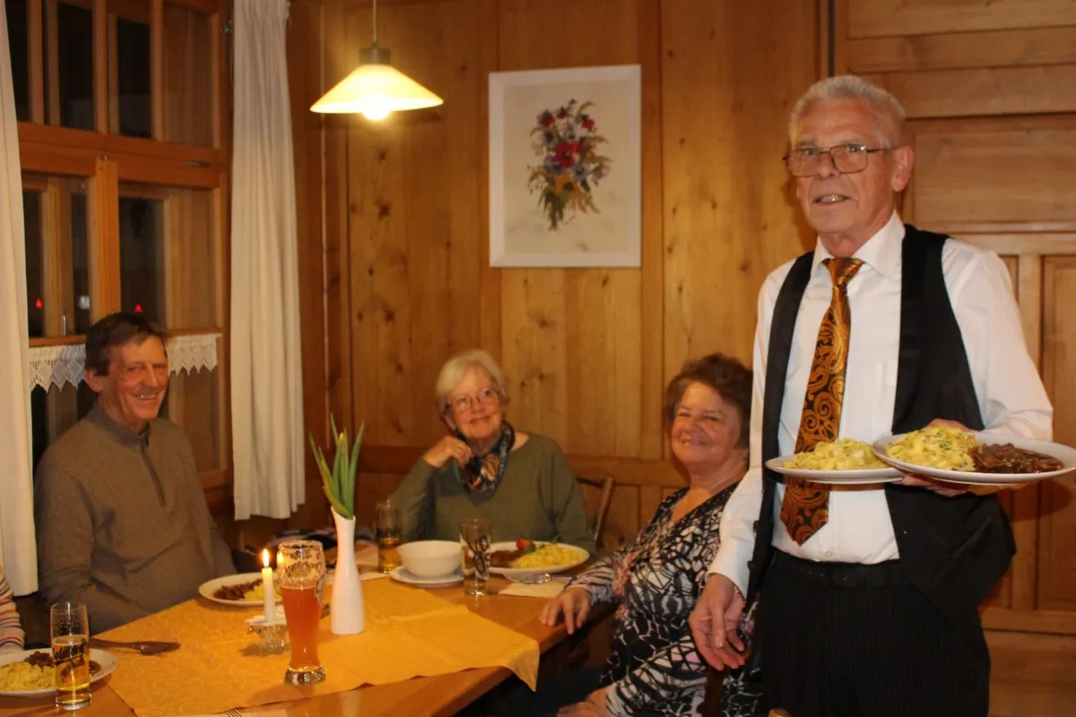 Kellner serviert Essen an Gäste in einem Restaurant mit Holzwänden