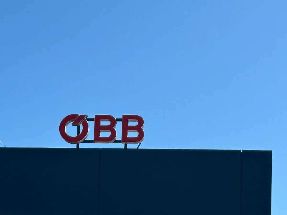 ÖBB-Logo auf dunkler Fassade vor blauem Himmel