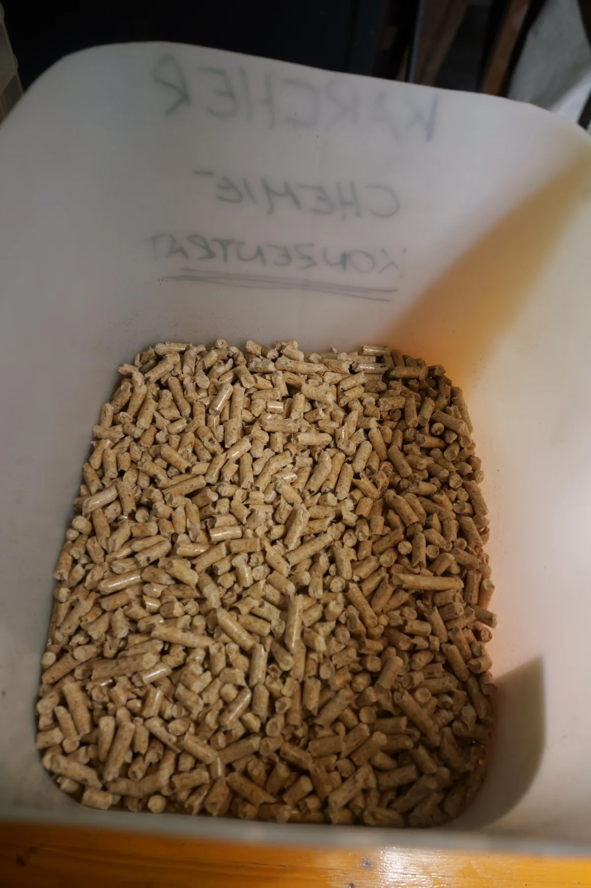 Holzpellets in weißem Behälter mit Aufschrift "KIRCHE-CHEMIE-KONSERV".