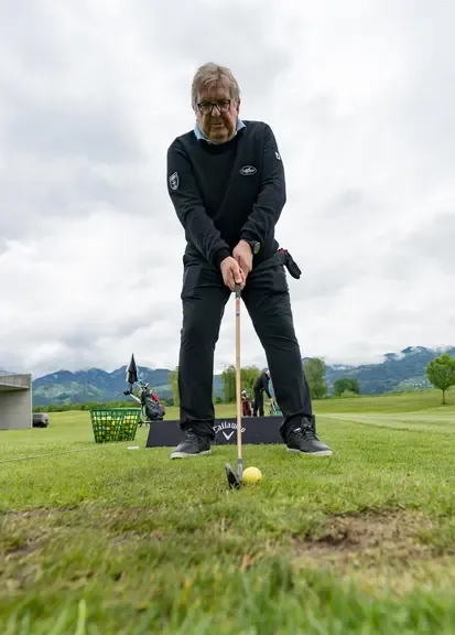 Golfspieler übt Abschlag auf einem Golfplatz in Österreich mit Bergen im Hintergrund.