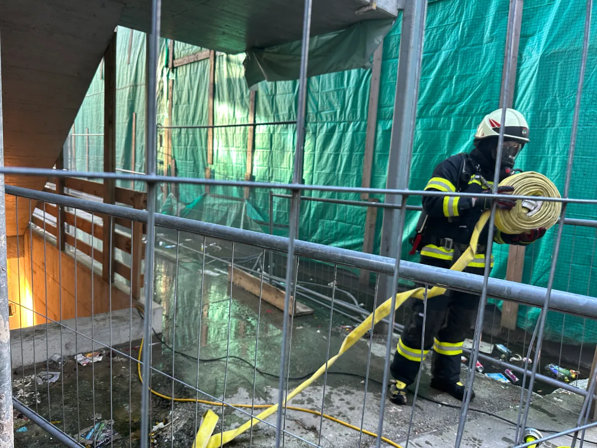 Feuerwehrmann mit Schlauch auf Baustelle in Wien