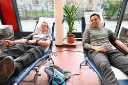Blutspende: Zwei Männer liegen in Liegestühlen und spenden Blut in einer Einrichtung.