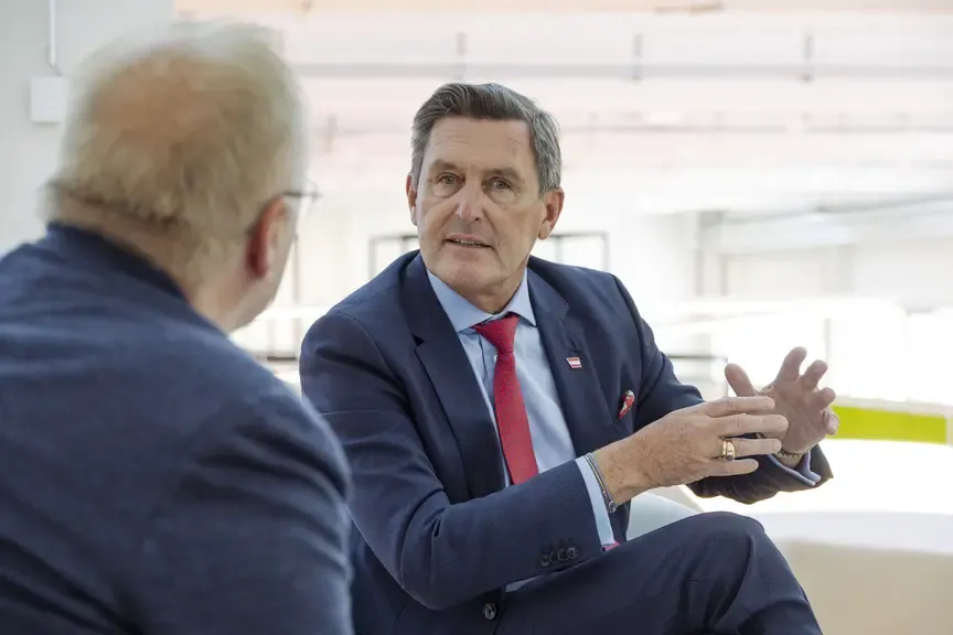 Michael Schickhofer spricht mit einem Mann in einem Anzug in einem hellen Raum.