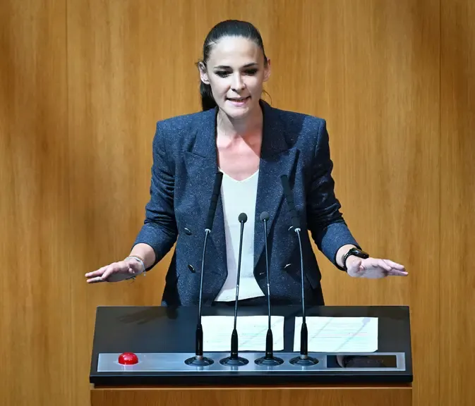 Bundesministerin Alma Zadić spricht vor Mikrofonen im Parlament in Wien