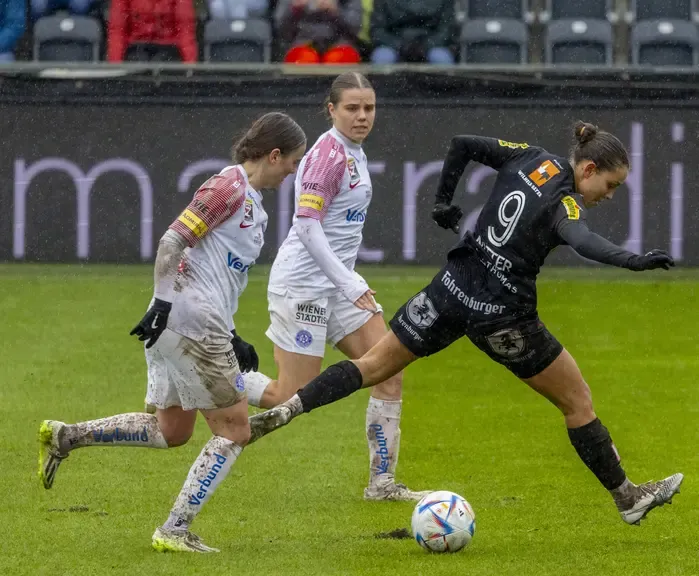 Fußballspielerin mit Ball auf grünem Rasen in Wien
