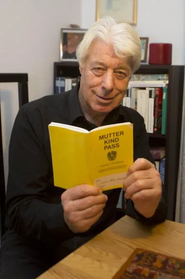 Mutter Kind Pass: Mann mit gelbem Buch vor Bücherregal in Wien