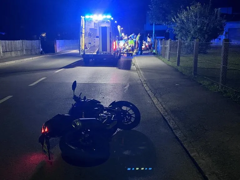 Motorradunfall mit Rettungseinsatz und Blaulicht auf der Fahrbahn in der Nacht
