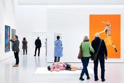 Menschen betrachten Kunstwerke in einer modernen Galerie in Wien.